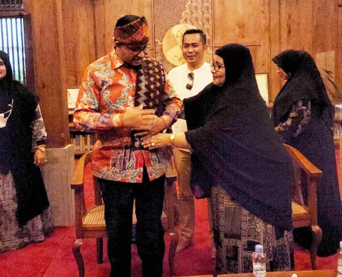Ummi Amnah memakaikan Tenun Bumi untuk Anies Baswedan. Foto istimewa
