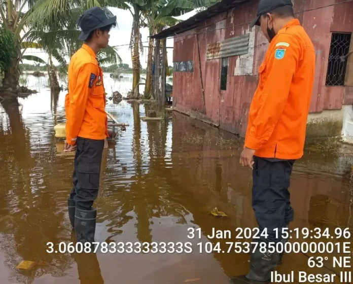 Personil BPBD Ogan Ilir, Sumatra Selatan memantau kondisi rumah warga yang tergenang banjir pada Rabu petang (31/1). (BPBD Kab. Ogan Ilir)